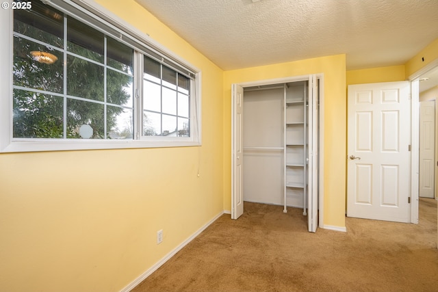 unfurnished bedroom with light colored carpet, a closet, and a textured ceiling