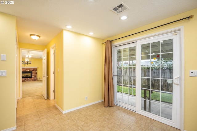 empty room featuring a brick fireplace, a textured ceiling, and ceiling fan