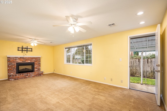 unfurnished living room with a brick fireplace, plenty of natural light, light colored carpet, and ceiling fan