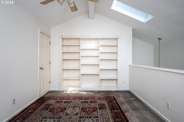 interior space with ceiling fan, beamed ceiling, a skylight, a textured ceiling, and carpet