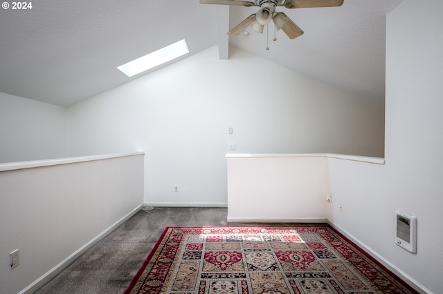 additional living space featuring heating unit, vaulted ceiling with skylight, carpet flooring, and ceiling fan