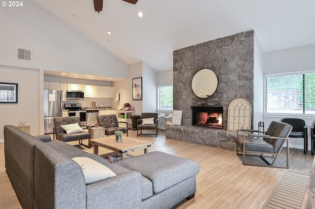 living room featuring light hardwood / wood-style floors, a fireplace, ceiling fan, and high vaulted ceiling