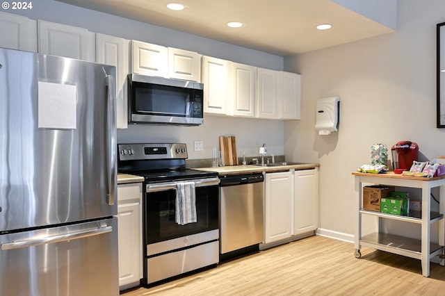 kitchen with white cabinets, appliances with stainless steel finishes, and light wood-type flooring