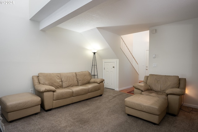 carpeted living room with a textured ceiling and vaulted ceiling with beams