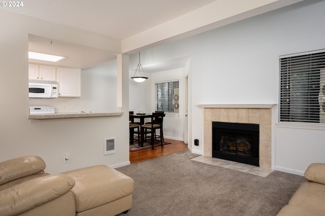 living room with heating unit, a fireplace, and light carpet