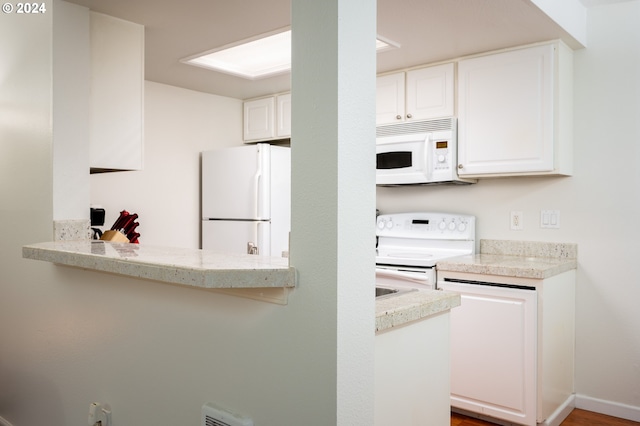 kitchen with white appliances, white cabinetry, hardwood / wood-style floors, and kitchen peninsula