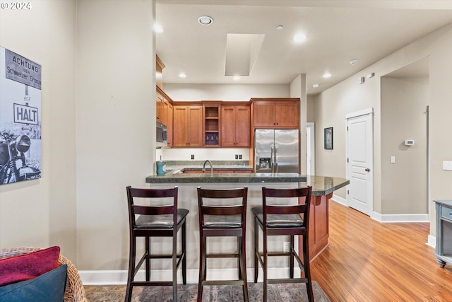 kitchen with stainless steel appliances, a breakfast bar area, sink, and light wood-type flooring