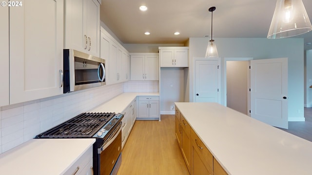 kitchen with light wood-type flooring, backsplash, white cabinetry, and range with gas stovetop