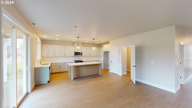 kitchen with light hardwood / wood-style floors, sink, plenty of natural light, and a kitchen island