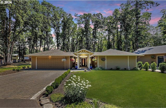 ranch-style home featuring a garage and a lawn