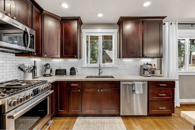 kitchen with sink, light hardwood / wood-style floors, tasteful backsplash, and stainless steel appliances