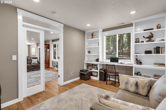 office space with built in desk and light hardwood / wood-style flooring