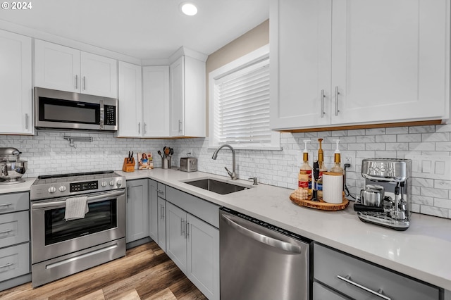 kitchen featuring light hardwood / wood-style flooring, appliances with stainless steel finishes, sink, white cabinets, and tasteful backsplash