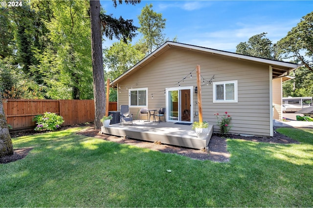 back of house featuring a wooden deck and a lawn