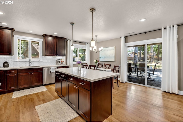 kitchen featuring dishwasher, hanging light fixtures, sink, a center island, and decorative backsplash