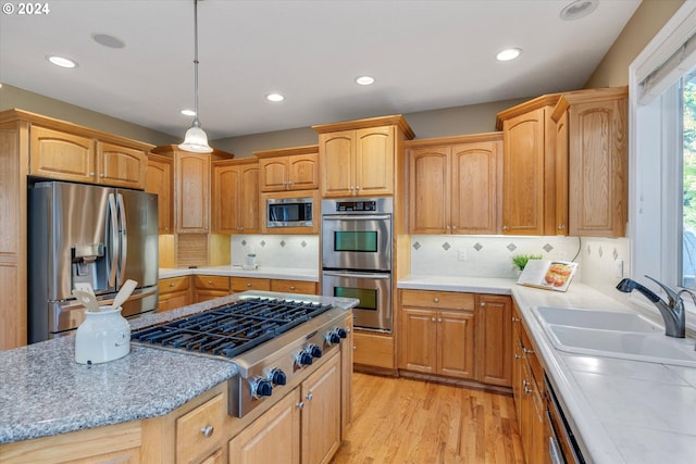 kitchen featuring decorative backsplash, stainless steel appliances, light hardwood / wood-style flooring, decorative light fixtures, and sink