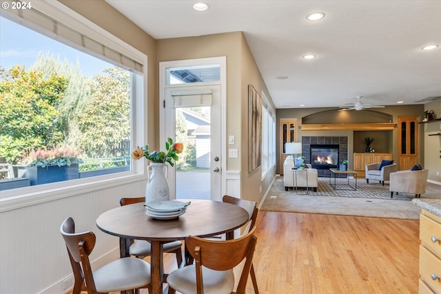 dining area with ceiling fan, plenty of natural light, light hardwood / wood-style floors, and a tile fireplace