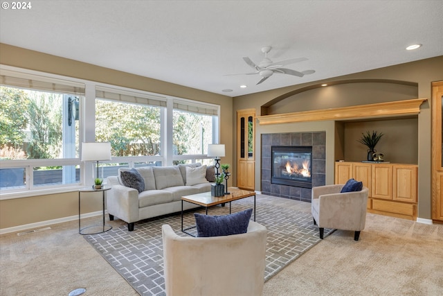 living room featuring a tile fireplace, carpet, and ceiling fan