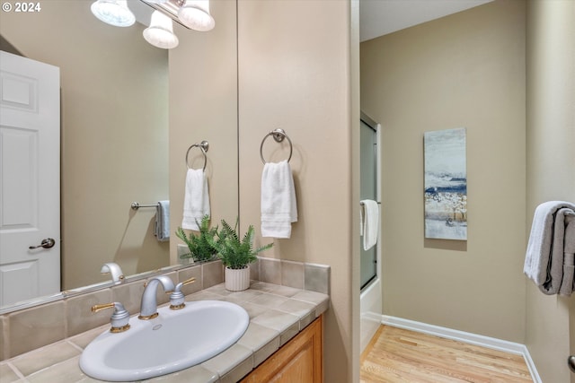 bathroom featuring vanity, hardwood / wood-style floors, and bath / shower combo with glass door