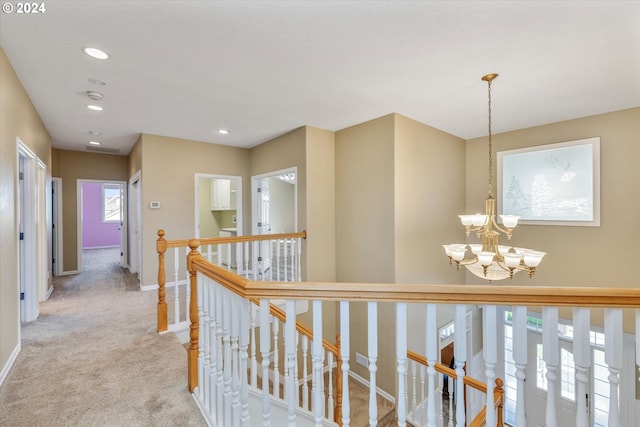 hall featuring light colored carpet and a notable chandelier