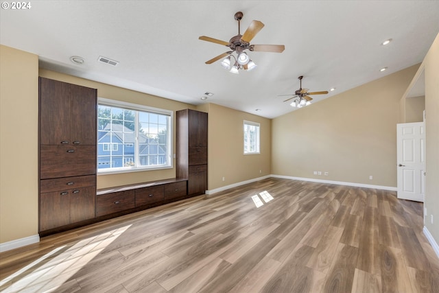 unfurnished living room featuring light hardwood / wood-style flooring, lofted ceiling, ceiling fan, and a healthy amount of sunlight