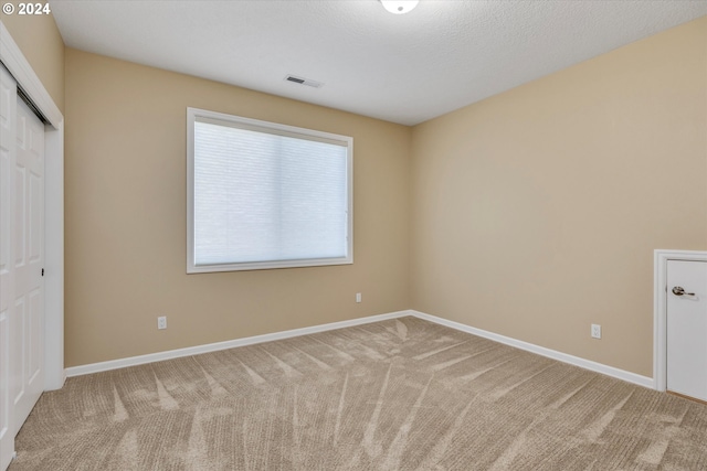 unfurnished bedroom with carpet floors, a textured ceiling, and a closet