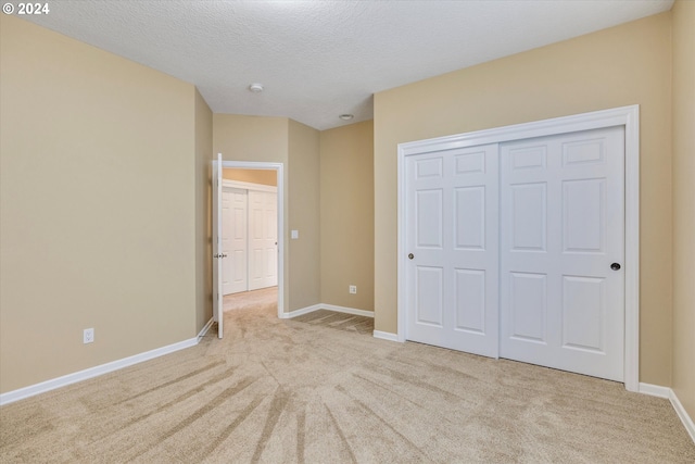 unfurnished bedroom with a closet, light colored carpet, and a textured ceiling