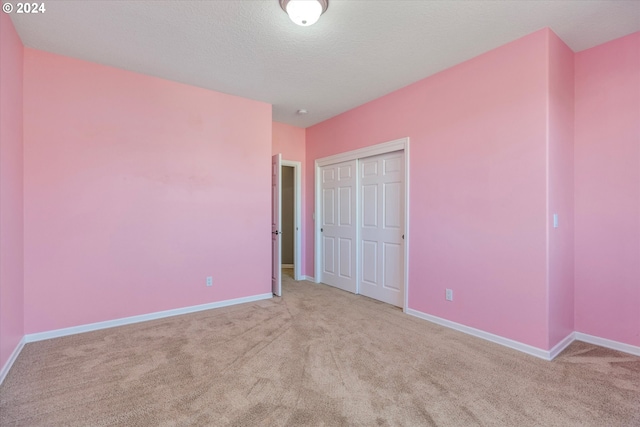 unfurnished bedroom with light carpet, a textured ceiling, and a closet