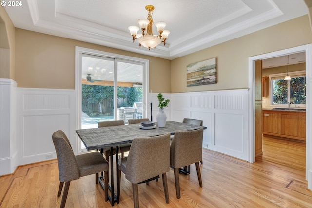 dining area featuring an inviting chandelier, a tray ceiling, and light wood-type flooring