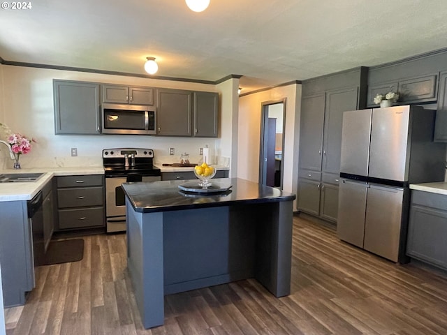 kitchen featuring a kitchen island, ornamental molding, stainless steel appliances, and dark wood-style flooring