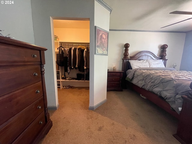 bedroom with ceiling fan, light colored carpet, baseboards, a closet, and a walk in closet