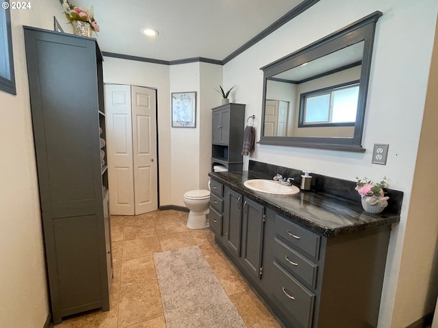 bathroom featuring toilet, vanity, baseboards, a closet, and crown molding