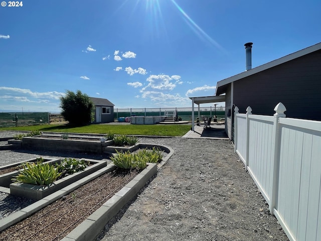 view of yard featuring a fenced backyard, a storage shed, an outdoor structure, a pool, and a vegetable garden