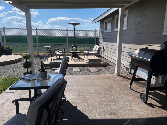 view of patio featuring area for grilling, fence, and a water view