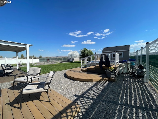 wooden terrace with a yard, a fenced backyard, and an outbuilding