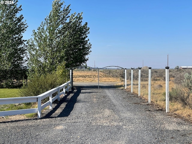 view of gate with fence and a rural view