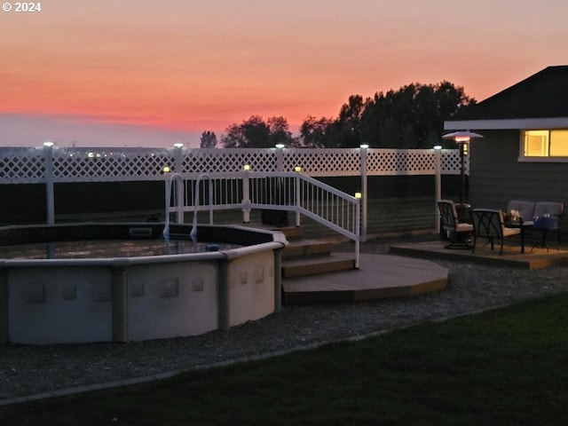 pool at dusk with a patio area and an outdoor pool