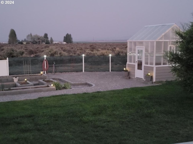 view of yard featuring an exterior structure, an outbuilding, a garden, and fence