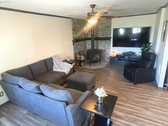 living area with a wood stove, ceiling fan, ornamental molding, and wood finished floors