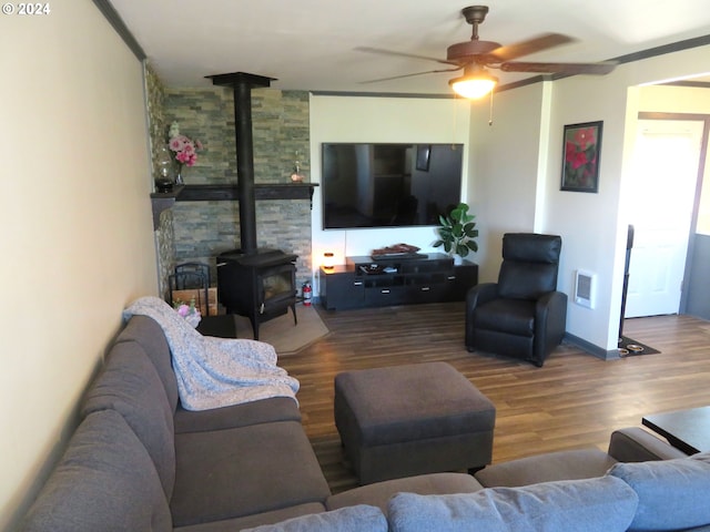 living room with a wood stove, visible vents, a ceiling fan, and wood finished floors