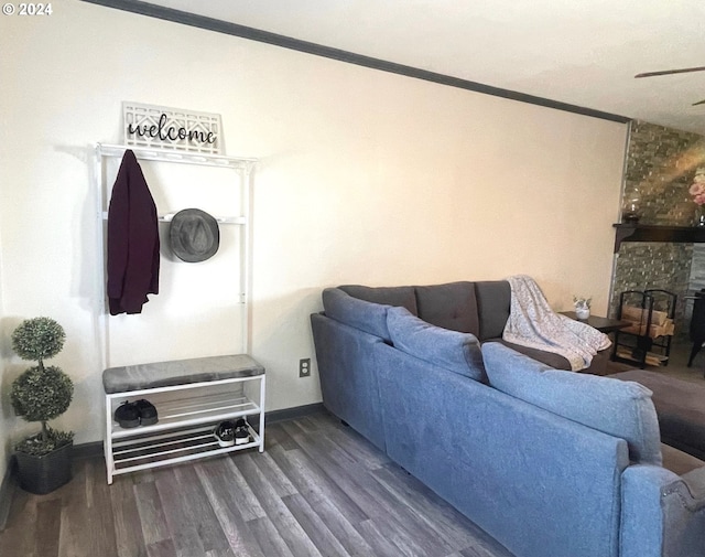 living area featuring dark wood-type flooring, a stone fireplace, and baseboards