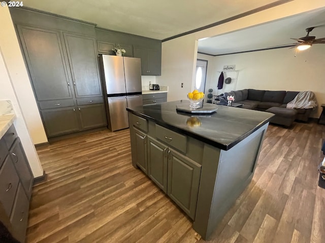 kitchen featuring freestanding refrigerator, a center island, dark countertops, and dark wood-style flooring