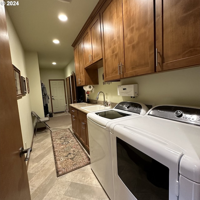 laundry room with washing machine and clothes dryer, cabinets, and sink