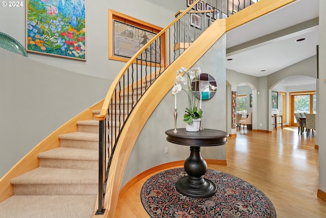 staircase with a towering ceiling and hardwood / wood-style floors