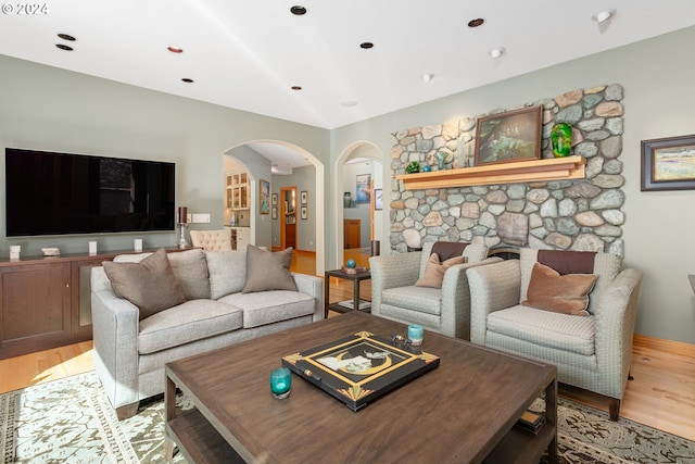 living room featuring a stone fireplace and light wood-type flooring