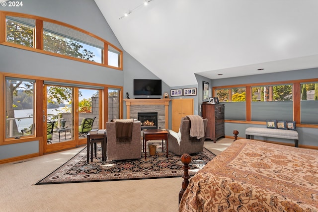 bedroom featuring high vaulted ceiling, access to outside, track lighting, carpet floors, and a tiled fireplace