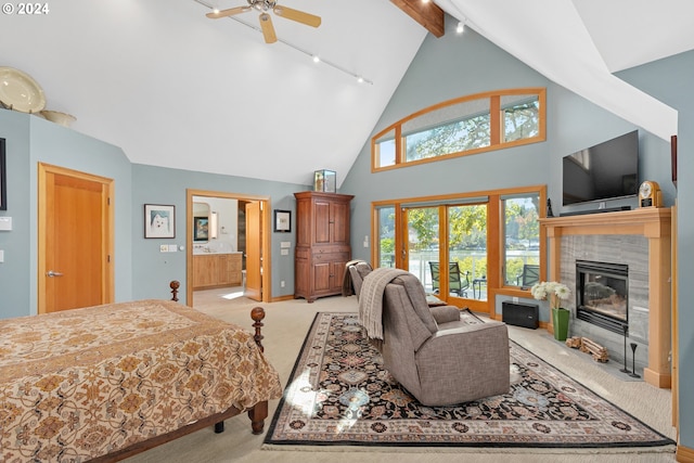 bedroom with high vaulted ceiling, a fireplace, rail lighting, light colored carpet, and ensuite bath