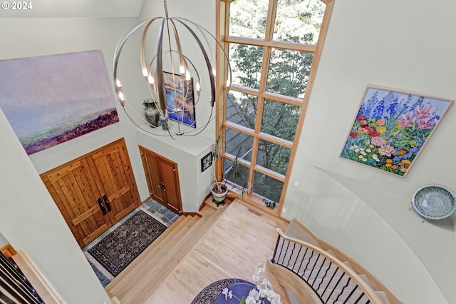 entryway with an inviting chandelier, light hardwood / wood-style floors, and a high ceiling