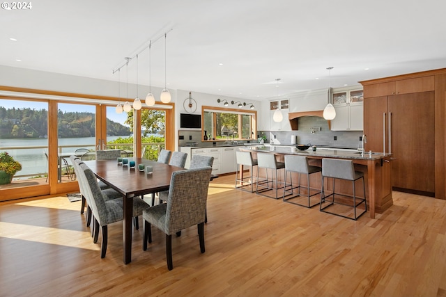 dining area featuring light hardwood / wood-style floors, rail lighting, and a water view