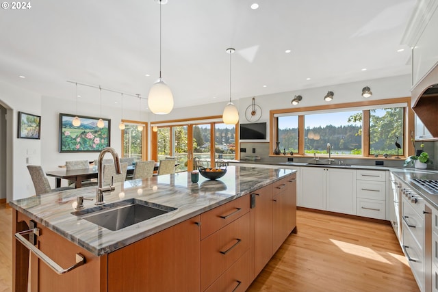 kitchen featuring sink, white cabinetry, pendant lighting, a large island, and light stone countertops